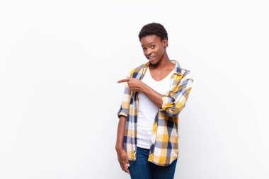 Genç ve güzel siyah kadın heyecanlı ve şaşırmış görünüyor. Yana ve yukarıya doğru uzayı gösteriyor.