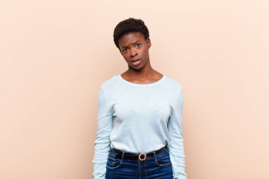 young pretty black womanfeeling puzzled and confused, with a dumb, stunned expression looking at something unexpected