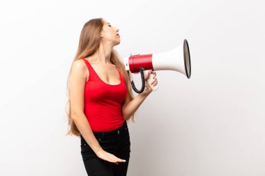 Profil görünümlü genç sarışın kadın megafon tutarak uzayı kopyalamaya çalışıyor, düşünüyor, hayal ediyor ya da hayal ediyor.