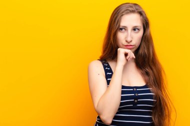 Genç sarışın kadın düşünüyor, kuşkulu ve şaşkın hissediyor, farklı seçeneklerle, hangi kararı vereceğini merak ediyor.