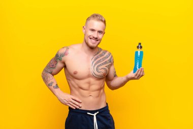 Genç sarışın güçlü adam gülümsüyor, kendinden emin, başarılı ve mutlu hissediyor, fotokopi alanında bir yandan enerji içeceği ile fikir veya konsept gösteriyor.