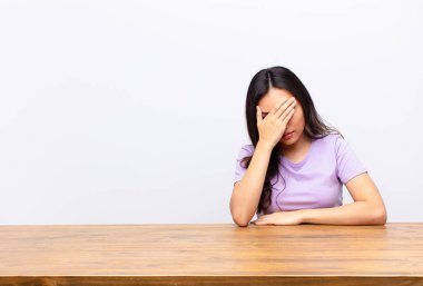 Genç, Latin, güzel bir kadın stresli, utanmış ya da üzgün görünüyordu. Başı ağrıyordu. Yüzü düz duvarla kaplıydı.