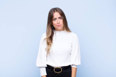 Genç ve güzel İspanyol kadın şaşkın ve kuşkulu hissediyor, merak ediyor ya da mavi duvara karşı karar vermeye çalışıyor.