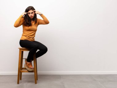 Genç, güzel bir kadın, ağzı açık bir şekilde bir odada otururken yüz yüze inanmayarak şok olmuş ve hayrete düşmüş hissediyor.