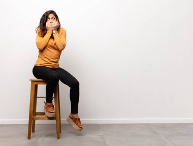 Genç, güzel bir kadın neşeyle gülümsüyor ve yan taraftaki fotokopi alanını işaret ediyor. Bir odanın içinde duran bir objeyi gösteriyor ya da reklamını yapıyor.