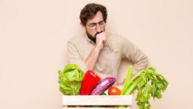 Yeşil bakkal boğazı ağrıyan ve grip belirtileri gösteren ağzı kapalı öksüren hasta bir adam.