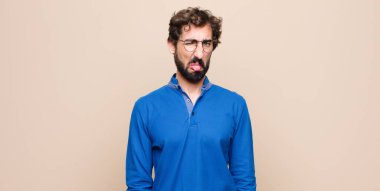 Genç yakışıklı adam iğreniyor ve rahatsız oluyor. Dilini dışarı çıkarıyor. Çirkin bir şeyden hoşlanmıyor ve düz duvara yaslanıyor.