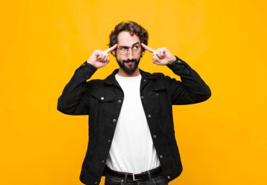 Genç, yakışıklı, kafası karışmış ya da şüpheye düşmüş, bir fikre odaklanmış, çok düşünen, turuncu duvara karşı uzayı kopyalamak isteyen bir adam.