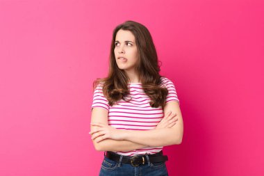 Genç, güzel bir kadın kuşkulanıyor ya da düşünüyor, dudağını ısırıyor ve kendini güvensiz ve gergin hissediyor. Kenarındaki boşluğu pembe duvara kopyalamak istiyor.