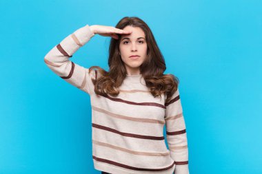 Genç ve güzel bir kadın, mavi duvara karşı saygı göstererek, onur ve vatanseverlik eylemiyle kamerayı selamlıyor.