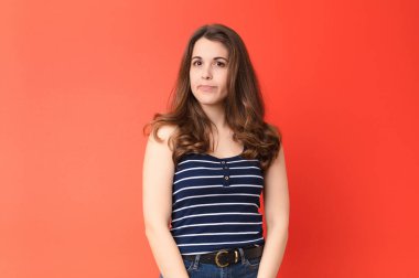 Genç, güzel bir kadın merak ediyor, mutlu düşünceler ve fikirler düşünüyor, hayal kuruyor, kırmızı duvara karşı uzayı kopyalamaya çalışıyor.