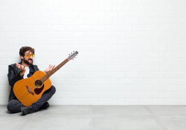 Gitarlı genç adam odada yerde yatıyor.