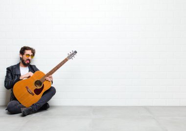 Odada gitarlı yakışıklı bir adam var.