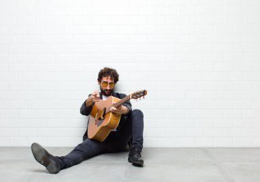 Duvarın arkasında gitar çalan genç adam.