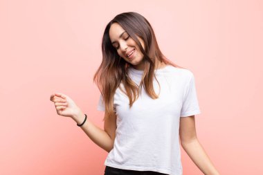 Genç, güzel bir kadın gülümsüyor, kaygısız, rahat ve mutlu hissediyor, dans ediyor ve müzik dinliyor, pembe duvarın karşısındaki bir partide eğleniyor.