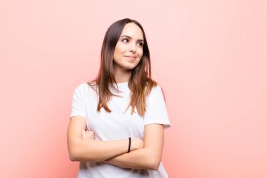 Genç, güzel bir kadın kendini mutlu, gururlu ve umutlu hissediyor, merak ediyor ya da düşünüyor, pembe duvara yaslanmış çapraz kollarıyla uzayın fotokopisini çekmek istiyor.