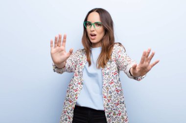 Genç ve güzel bir kadın korku ve panik içinde geri çekilip çığlık atıyor. Mavi duvara karşı bir kabusa tepki veriyor.