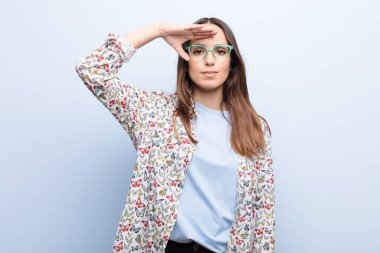 Genç ve güzel bir kadın, mavi duvara karşı saygı göstererek, onur ve vatanseverlik eylemiyle kamerayı selamlıyor.