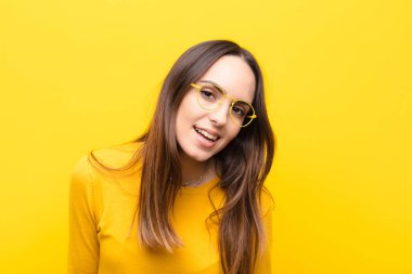 Büyük, dostane, kaygısız bir gülümsemesi olan genç, güzel bir kadın. Olumlu, rahat ve mutlu görünüyor. Turuncu duvarda takılıyor.