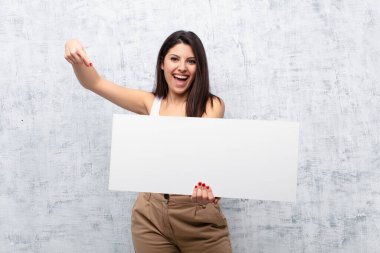 Genç ve güzel bir kadın grunge duvarına pankart asıyor.