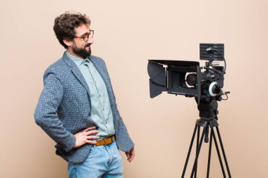 Televizyon sunucusu mutlu bir şekilde gülümsüyor. Kendine güvenen, olumlu, gururlu ve arkadaş canlısı bir tavırla.