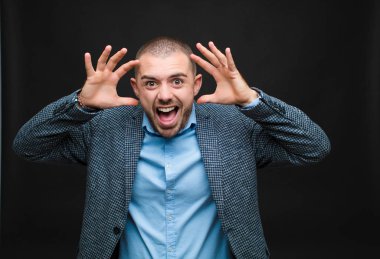 Genç işadamı panik ya da öfke içinde bağırıyor, şok olmuş, korkmuş ya da öfkeli, elleri düz duvara dayalı.