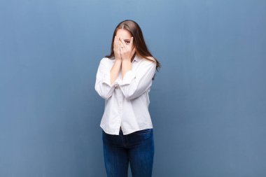 Genç sarışın güzel kız korkmuş ya da utanmış hissediyor, dikizliyor ya da gözleri yarı kapalı beton duvara bakıyor.