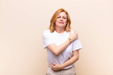 Orta yaşlı bir kadın endişeli, hasta, hasta ve mutsuz hissediyor. Ağrılı bir mide ağrısı veya grip geçiriyor.