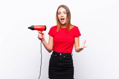 Kızıl saçlı güzel bir kadın şok olmuş ve şaşırmış, endişeli ve paniklemiş hissediyor. Stresli ve dehşete kapılmış bir şekilde elinde kuaförle bakıyor.