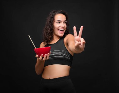 Genç, güzel bir kadın gülümsüyor ve arkadaş canlısı görünüyor. İki numarayı gösteriyor. Elleri önde, geriye doğru sayıyor.