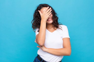 Genç, güzel bir kadın stresli, utanmış ya da üzgün görünüyor. Başı ağrıyor, yüzü mavi arka planda.