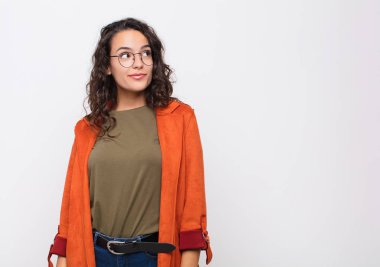 Genç, güzel bir kadın merak ediyor, mutlu düşünceler ve fikirler düşünüyor, hayal kuruyor, beyaz duvara karşı uzayı kopyalamaya çalışıyor.