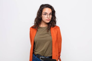 Genç, güzel bir kadın üzgün ve stresli. Kötü bir sürpriz yüzünden üzgün. Olumsuz, endişeli bir bakışla beyaz duvara bakıyor.