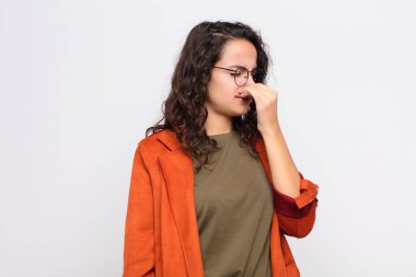 Genç ve güzel bir kadın iğreniyor, pis ve tatsız bir kokuyu beyaz duvarda hissetmemek için burnunu tutuyor.