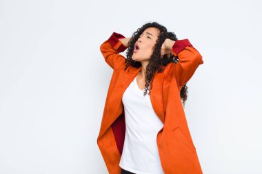 Genç siyah kadın ağzı açık, korkunç ve şok olmuş görünüyor, korkunç bir hata yüzünden, beyaz duvara karşı el kaldırıyor.