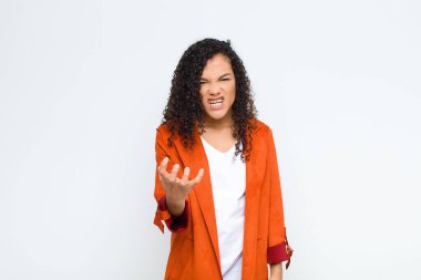 Genç siyah kadın kızgın, sinirli ve hayal kırıklığına uğramış görünüyor. Beyaz duvara karşı senin neyin var? 