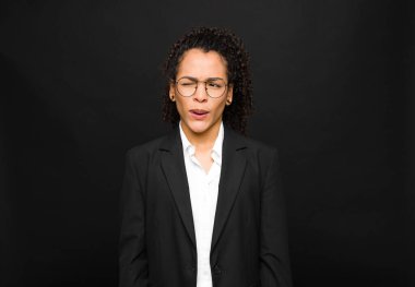 Genç siyahi kadın şapşal ve komik görünüyor. Aptal şaşı bir ifadeyle, şakalaşıyor ve siyah duvara karşı oynaşıyor.