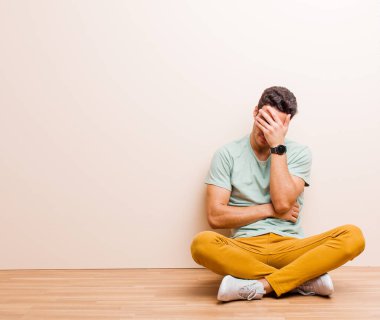 Genç Arap bir adam stresli, utanmış ya da üzgün görünüyordu. Baş ağrısı vardı. Yüzü elleri yerde oturuyordu.