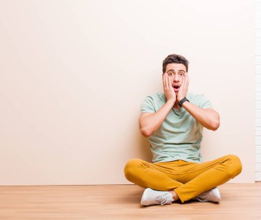 Genç Arap adam hoş olmayan bir şekilde şok olmuş, korkmuş ya da endişeli görünüyor, ağzı sonuna kadar açık ve iki kulağını da yerde oturarak kapatıyor.