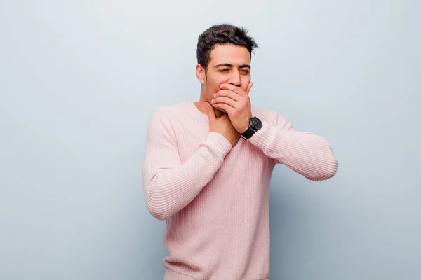 喉やインフルエンザの症状を患っている若いアラビア人男性は 灰色の壁に覆われた口で咳をします — ストック写真