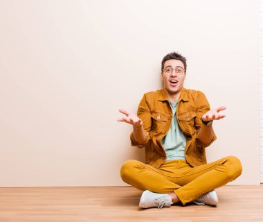 Genç Arap bir adam şok olmuş, şaşırmış, endişeli ve paniklemiş bir şekilde yerde oturuyor.