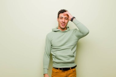 Genç Arap adam mutlu, şaşkın ve şaşırmış görünüyor, gülümsüyor ve düz duvara karşı inanılmaz ve inanılmaz iyi haberler veriyor.