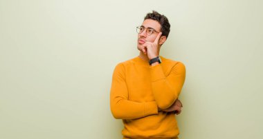 Yoğun bakışlı genç bir Arap adam, şüpheli bir ifadeyle merak ediyor, düz duvara bakıp duruyor.