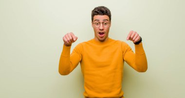 Genç Arap adam şok olmuş, ağzı açık ve şaşkın, inançsızlıkla bakıyor ve düz duvara karşı şaşırıyor.