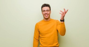 Genç Arap adam mutlu, şaşırmış ve neşeli, pozitif bir tavırla gülümseyen, düz duvara karşı bir çözüm ya da fikir gerçekleştiren