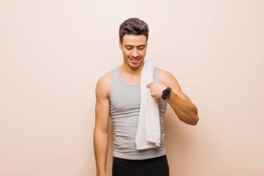 Genç Arap adam neşeyle ve gelişigüzel gülümsüyor aşağıya bakıyor ve göğsünü işaret ediyor. spor konsepti