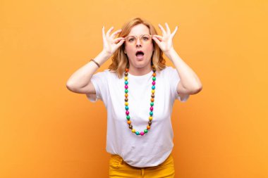 Orta yaşlı kadın şaşkın, şaşırmış ve şaşırmış hissediyor, elinde şaşkın, inançsız bir bakışla gözlük tutuyor.