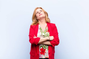 Orta yaşlı bir kadın mutlu, gururlu ve umutlu, merak ediyor ya da düşünüyor, çapraz kollarla fotokopi çekmeyi bekliyor.