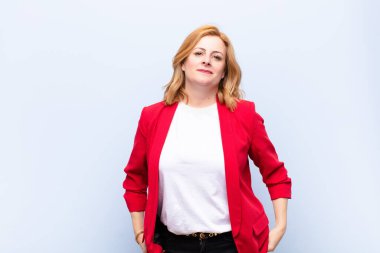 Orta yaşlı bir kadın mutlu, mutlu, kendinden emin ve rahat bir ifadeyle neşeli bir şekilde gülümsüyor.