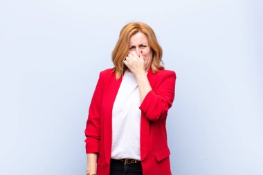 Orta yaşlı bir kadın iğrenç ve nahoş bir koku almaktan kaçınmak için burnunu tutuyor.